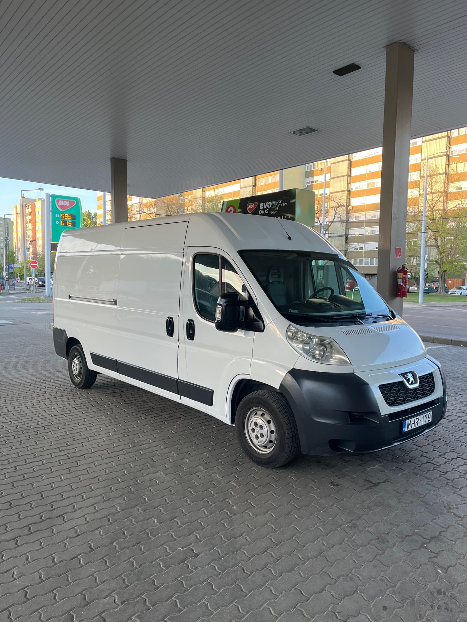 A Hiper Fuvar fehér Peugeot Boxer furgonja egy benzinkút tetője alatt