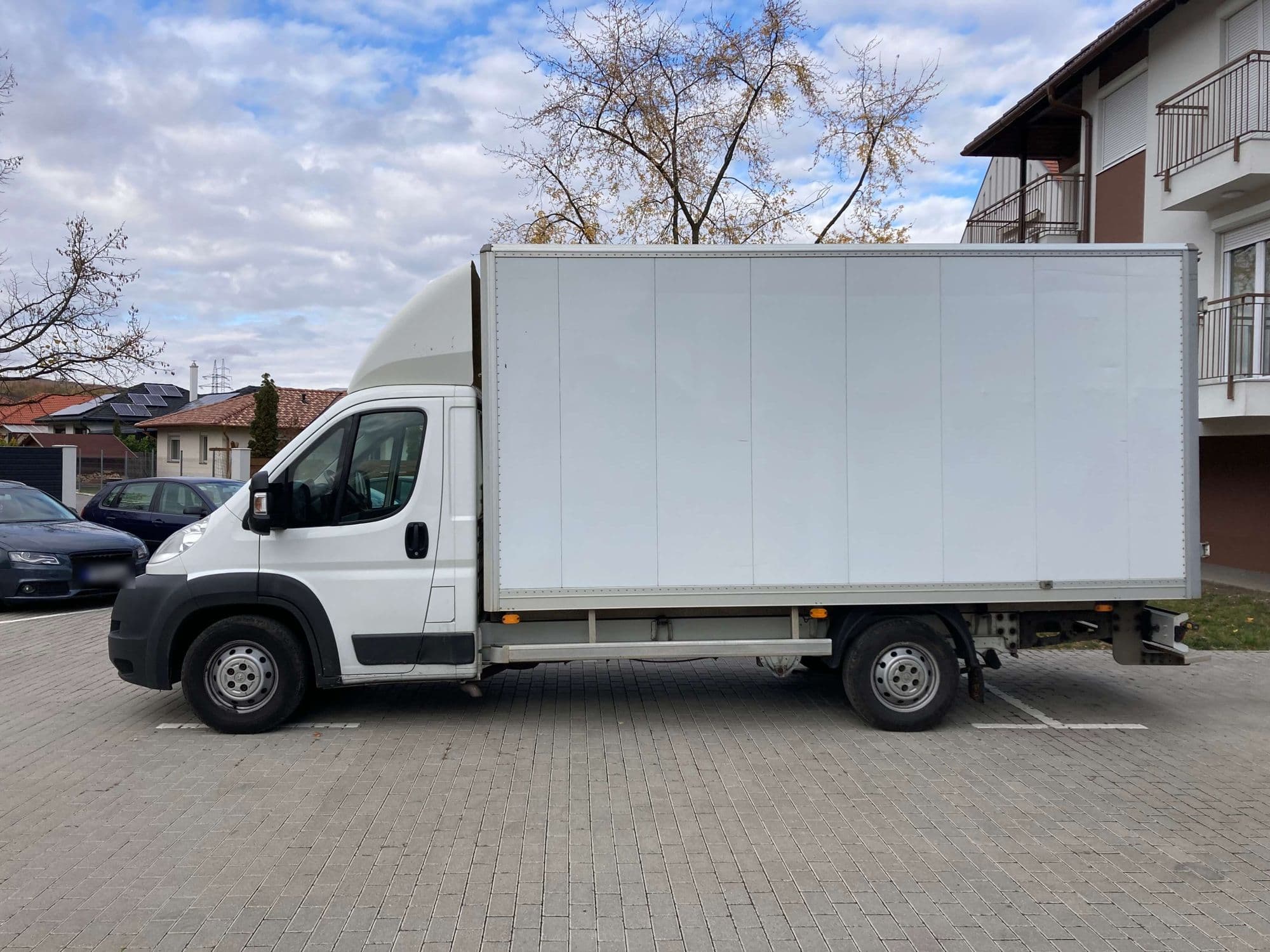 A Hiper Fuvar fehér Peugeot Boxer dobozos teherautója oldalról, társasház előtt
